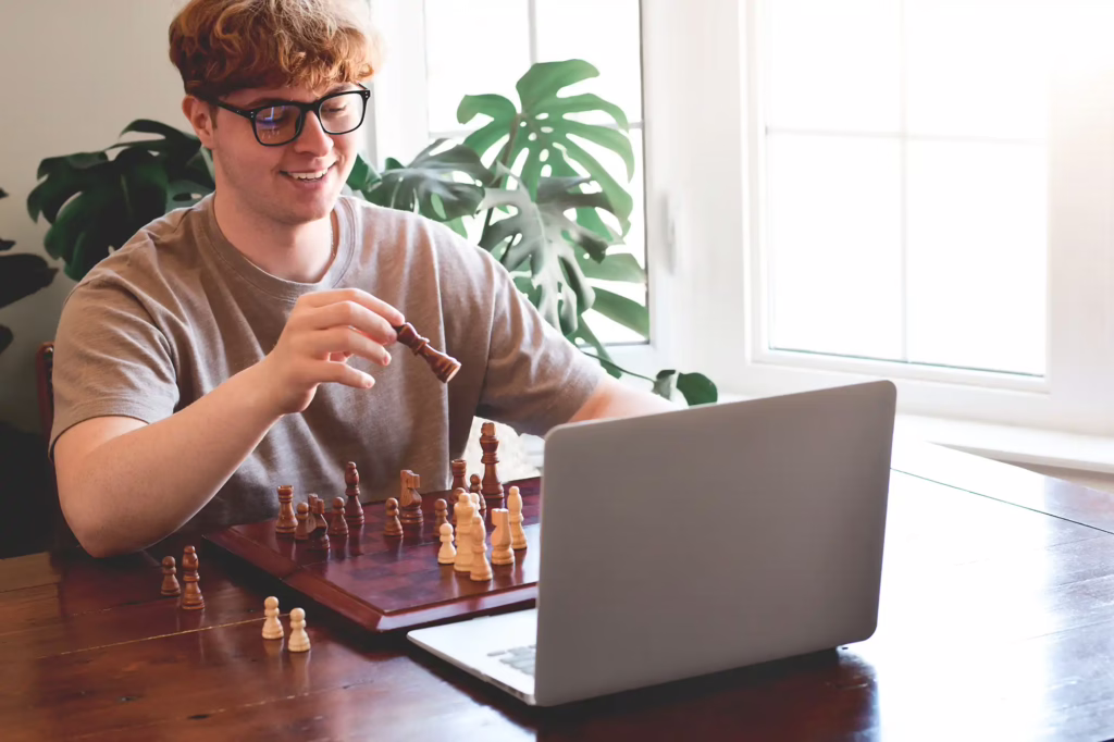 Hybridmodelle Schachtraining young man smiling while playing chess with a friend